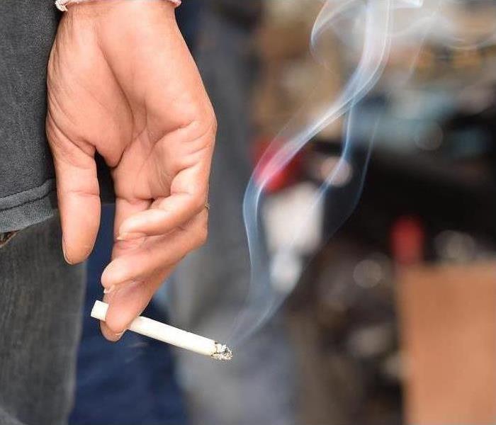 man holding smoking a cigarette in hand. Cigarette smoke spread. dark background