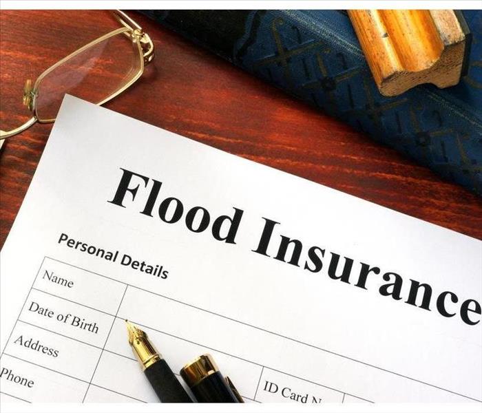Flood insurance form on a table with a book.